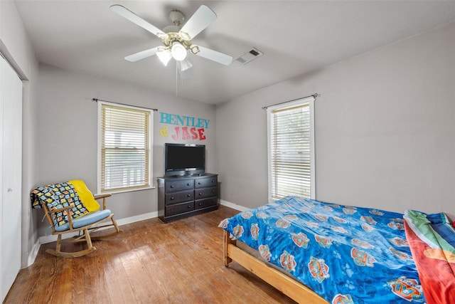 bedroom with a closet, visible vents, baseboards, a ceiling fan, and hardwood / wood-style floors