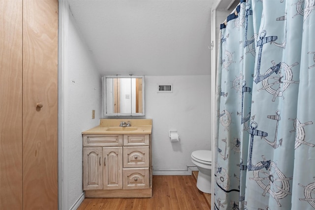 bathroom featuring visible vents, baseboards, wood finished floors, toilet, and vaulted ceiling