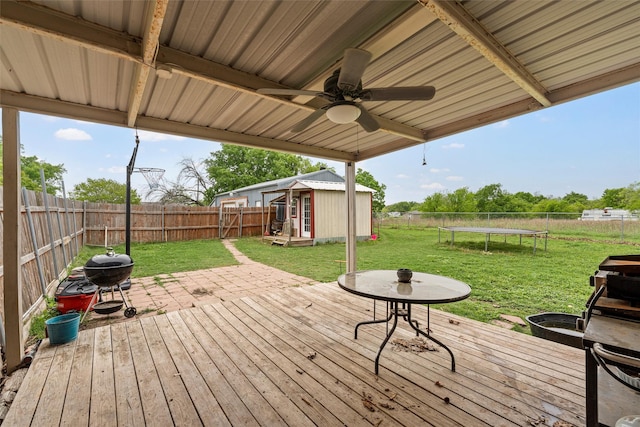 deck with an outbuilding, a trampoline, a yard, and a fenced backyard