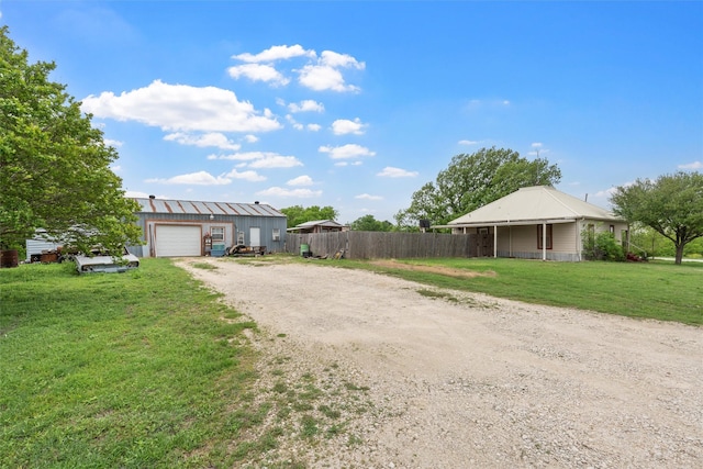 view of front of property featuring fence, a garage, a front yard, driveway, and an outbuilding
