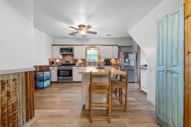 kitchen featuring white cabinetry, a sink, appliances with stainless steel finishes, and light wood-type flooring
