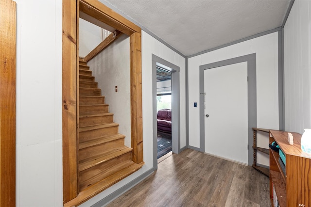 entrance foyer featuring a textured ceiling, stairs, and wood finished floors