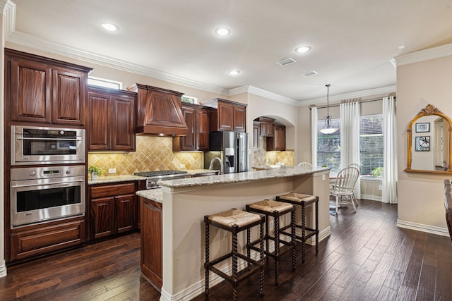 4513 Cherokee Dr, Mckinney, TX 75072 - kitchen with custom exhaust hood, a kitchen breakfast bar, dark wood finished floors, arched walkways, and appliances with stainless steel finishes