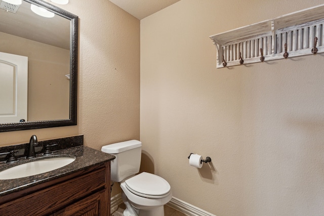 4513 Cherokee Dr, Mckinney, TX 75072 - half bathroom with a textured wall, vanity, baseboards, and toilet