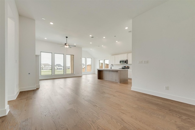 unfurnished living room with a ceiling fan, baseboards, vaulted ceiling, and light wood-style flooring