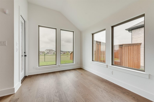 unfurnished room featuring baseboards, vaulted ceiling, and wood finished floors