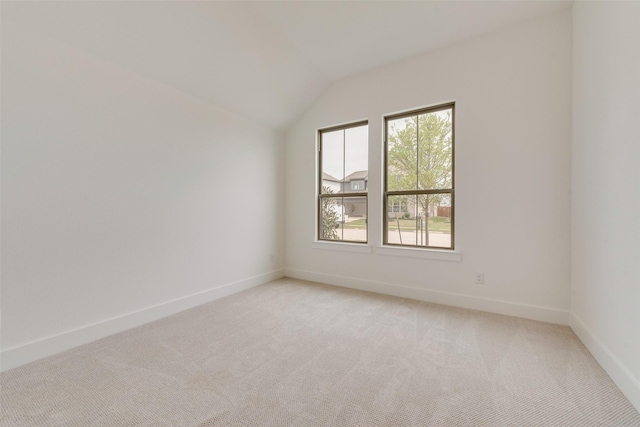empty room featuring baseboards, light colored carpet, and lofted ceiling