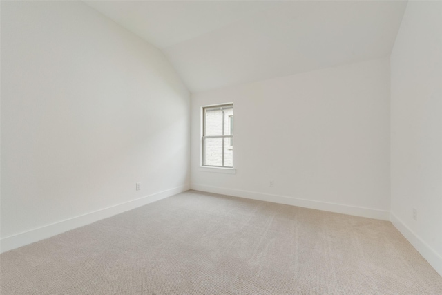 unfurnished room with baseboards, light carpet, and lofted ceiling