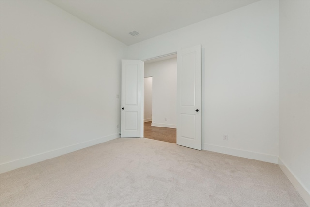 carpeted empty room featuring baseboards and visible vents