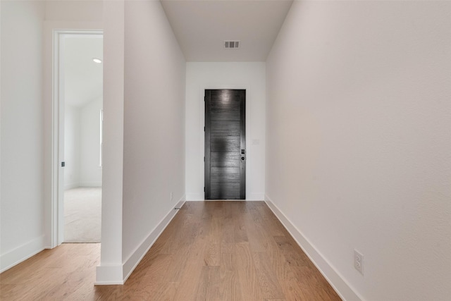 corridor with baseboards, light wood finished floors, and visible vents