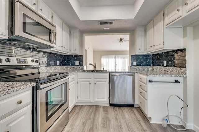 4539 N O Connor Rd Unit 2233, Irving, TX 75062 - kitchen featuring stainless steel appliances, light wood-style flooring, white cabinets, a raised ceiling, and a sink