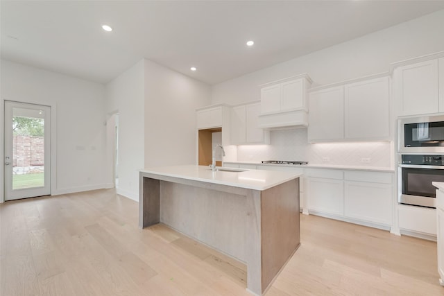 1151 Nora Ln, Forney, TX 75126 - kitchen with appliances with stainless steel finishes, a sink, light wood-style floors, tasteful backsplash, and white cabinetry