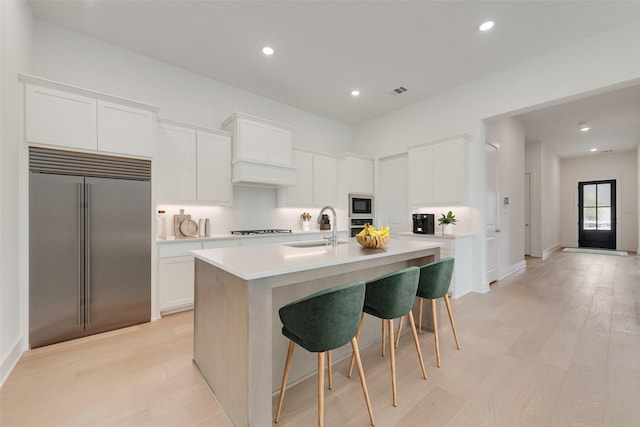 1151 Nora Ln, Forney, TX 75126 - kitchen with built in appliances, a sink, a center island with sink, decorative backsplash, and light countertops