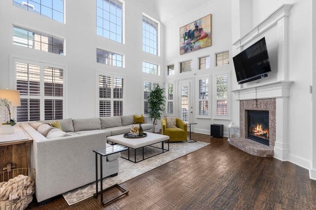 living area featuring ornamental molding, baseboards, a high ceiling, and a brick fireplace