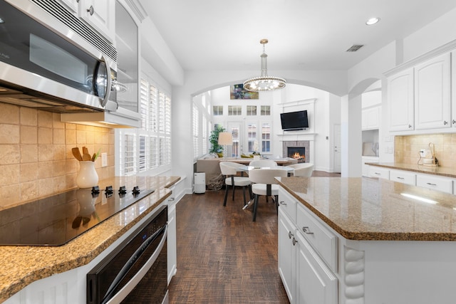 1891 Mustang Trl, Frisco, TX 75033 - kitchen featuring stainless steel microwave, oven, black electric stovetop, arched walkways, and recessed lighting