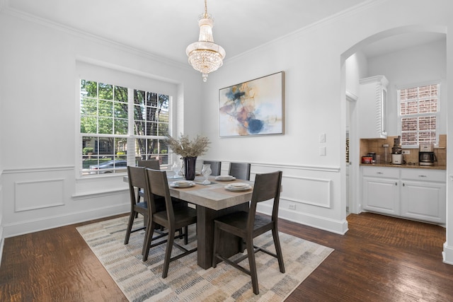 dining space with arched walkways, dark wood-style floors, and ornamental molding