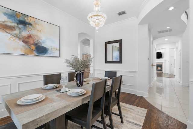 dining room featuring arched walkways, a notable chandelier, visible vents, and ornamental molding