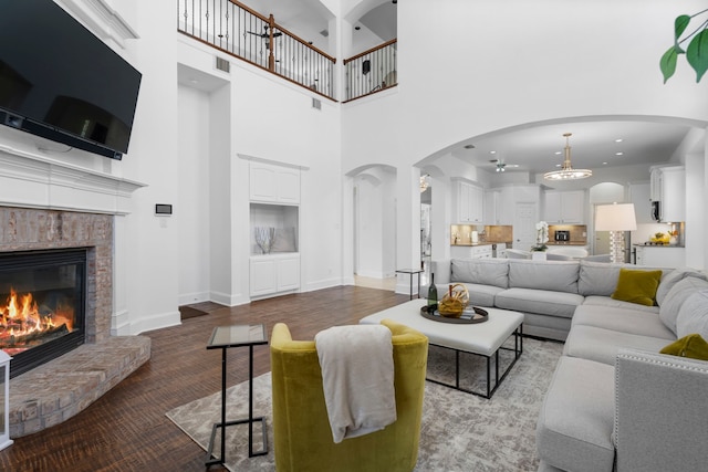1891 Mustang Trl, Frisco, TX 75033 - living room with a fireplace, a high ceiling, arched walkways, and wood finished floors