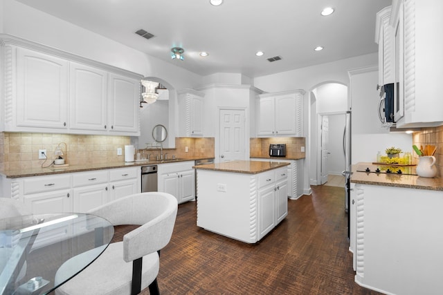 1891 Mustang Trl, Frisco, TX 75033 - kitchen with arched walkways, stainless steel microwave, light stone counters, recessed lighting, and decorative backsplash