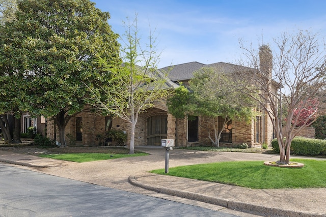 obstructed view of property featuring brick siding, a front yard, and a chimney