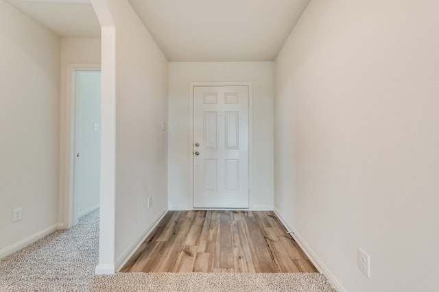 interior space with arched walkways, baseboards, and light wood finished floors