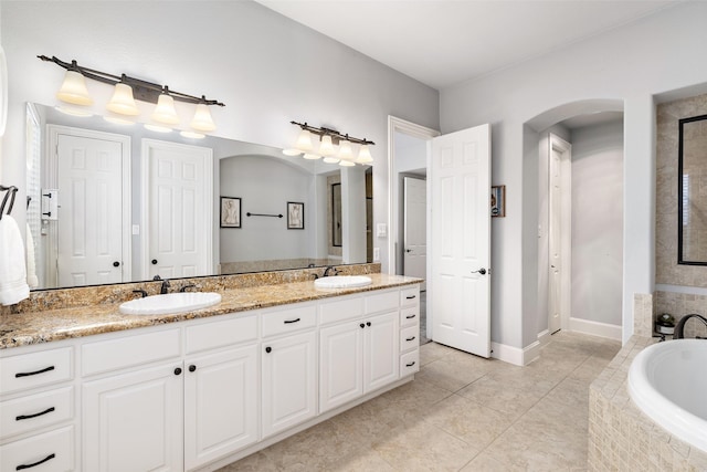 bathroom with double vanity, a garden tub, tile patterned flooring, and a sink