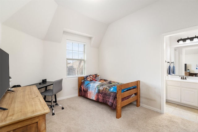 bedroom with vaulted ceiling, a sink, ensuite bathroom, light carpet, and baseboards