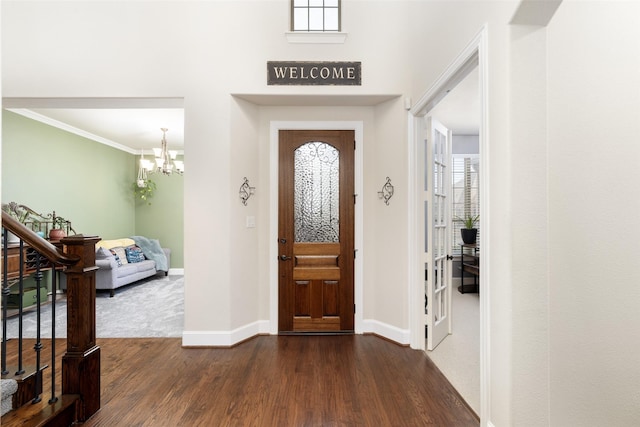 foyer with stairs, a chandelier, dark wood finished floors, baseboards, and ornamental molding