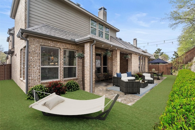 back of house with a fenced backyard, a patio area, an outdoor hangout area, and brick siding