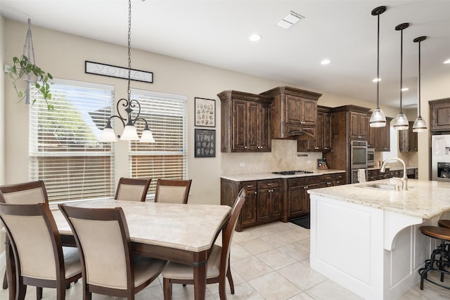kitchen featuring dark brown cabinets, visible vents, a sink, decorative backsplash, and gas stovetop