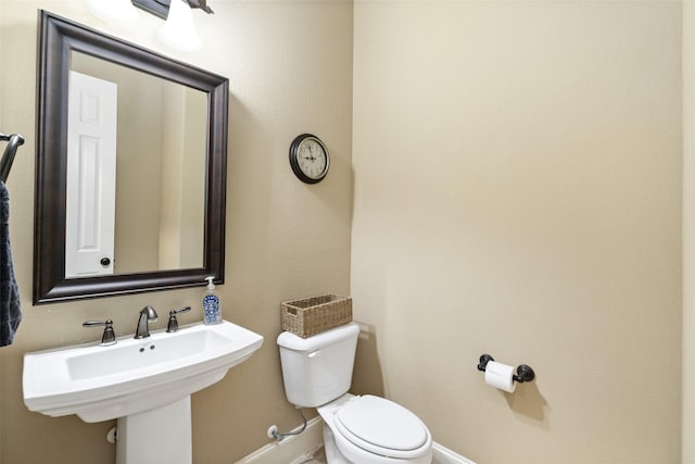 bathroom featuring toilet, a sink, and baseboards