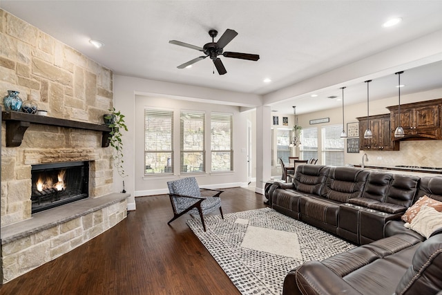 living room with recessed lighting, a stone fireplace, dark wood-style floors, and ceiling fan
