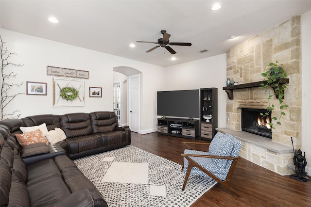 living room with a ceiling fan, wood finished floors, arched walkways, a fireplace, and visible vents