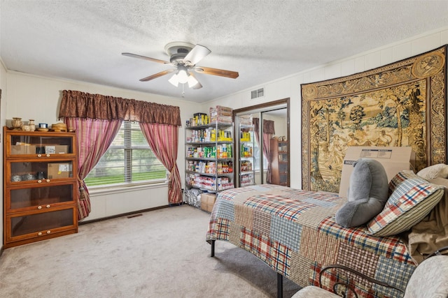 bedroom featuring carpet floors, a textured ceiling, ceiling fan, and visible vents