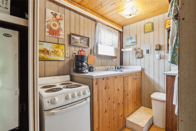 kitchen with light countertops, wooden walls, white appliances, a sink, and wood ceiling