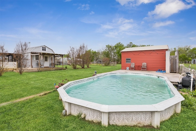 pool with a wooden deck, an outbuilding, fence, and a lawn