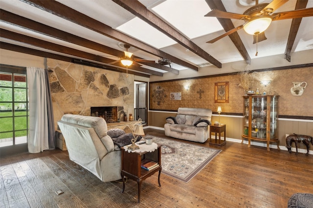 living area with wood-type flooring, wainscoting, beamed ceiling, and a ceiling fan