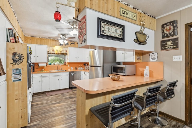 kitchen featuring white cabinetry, a sink, ceiling fan, a peninsula, and appliances with stainless steel finishes