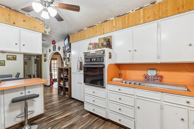 kitchen featuring dark wood-style floors, a ceiling fan, light countertops, and black oven