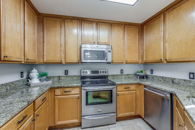 845 County Road 490, Princeton, TX 75407 - kitchen with light tile patterned floors, light stone countertops, appliances with stainless steel finishes, and brown cabinetry