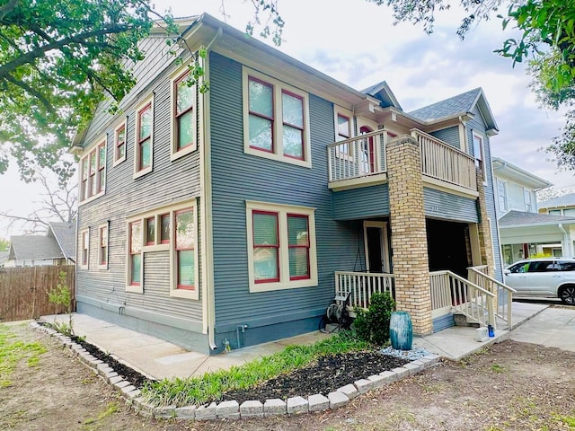 view of property exterior with a balcony, a porch, and fence