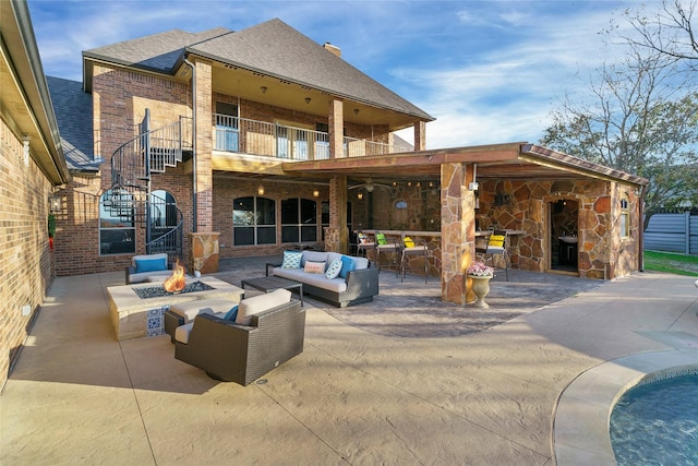 back of property with a patio area, an outdoor living space with a fire pit, a balcony, and a shingled roof