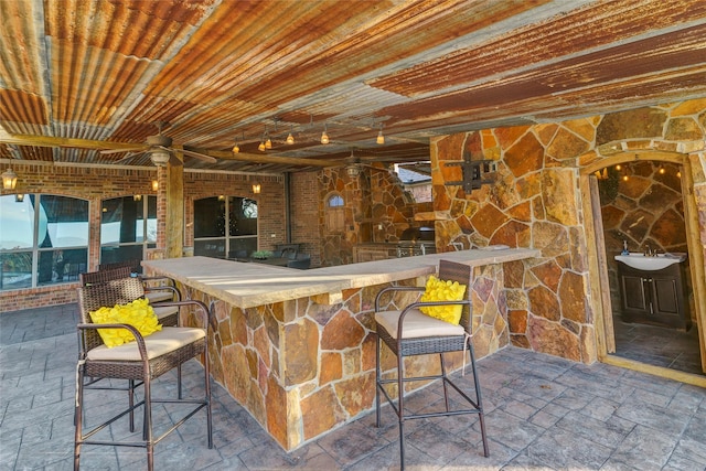 interior space featuring stone tile flooring, a ceiling fan, and a sink