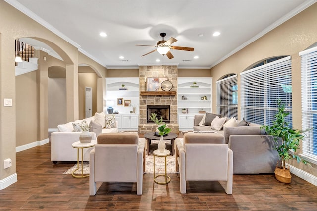 living area with arched walkways, dark wood finished floors, ornamental molding, and ceiling fan