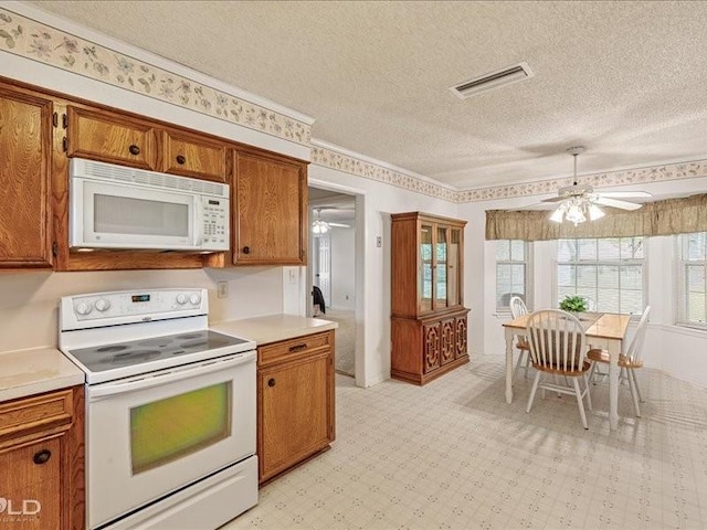 kitchen with visible vents, white appliances, a ceiling fan, light floors, and brown cabinetry