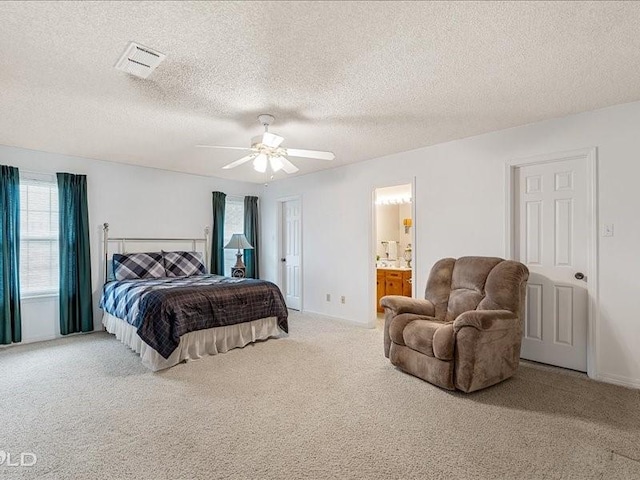 bedroom with ensuite bathroom, a textured ceiling, visible vents, a ceiling fan, and carpet floors