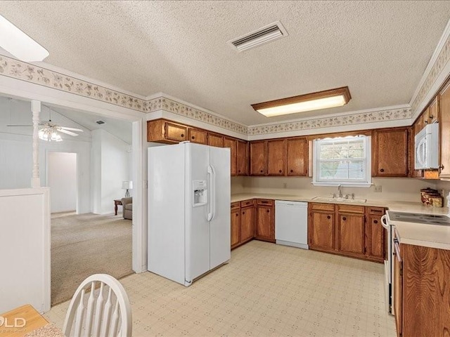 kitchen featuring visible vents, a sink, brown cabinetry, and white appliances