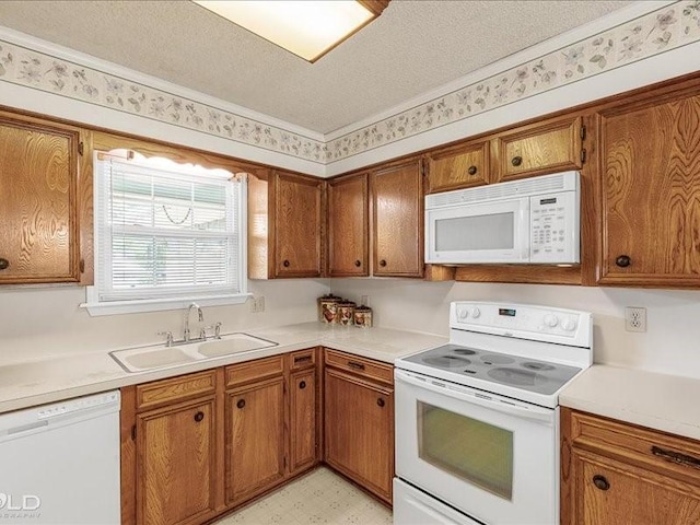kitchen with white appliances, a textured ceiling, a sink, brown cabinets, and light floors