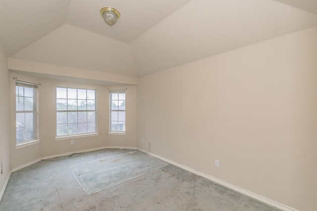 empty room with baseboards, vaulted ceiling, and light carpet