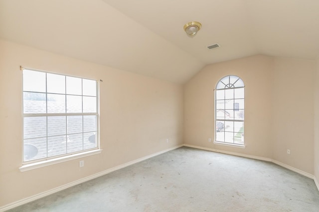 carpeted spare room featuring baseboards, visible vents, and vaulted ceiling